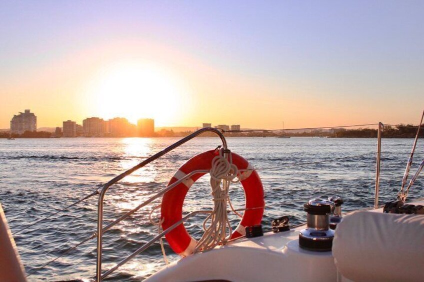 A boat with a red lifebuoy and a city skyline in the background during sunset. 4