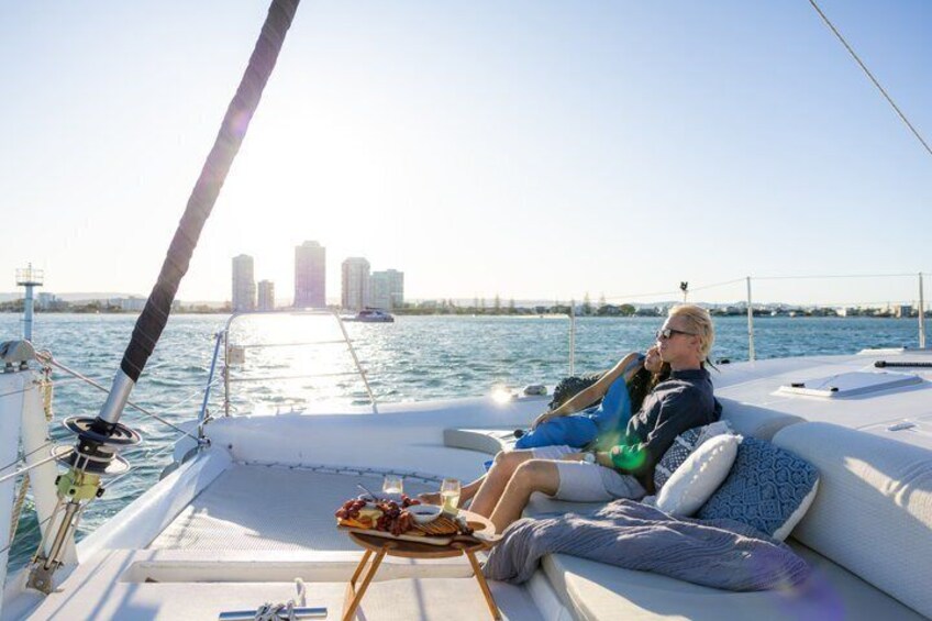 A couple relaxing on a sailboat with a city skyline in the background. 1