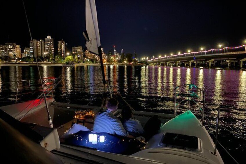 A nighttime sailboat with a city skyline in the background. 2