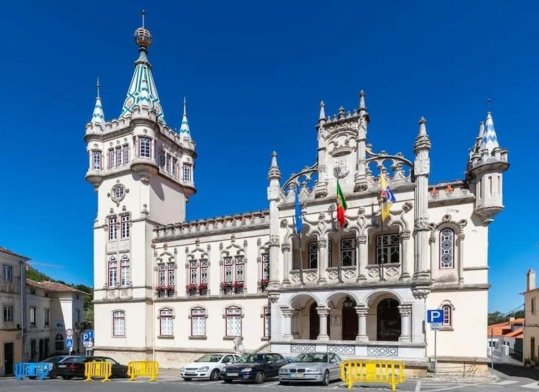 A historic building with ornate architecture, multiple flags, and a clear blue sky. 1