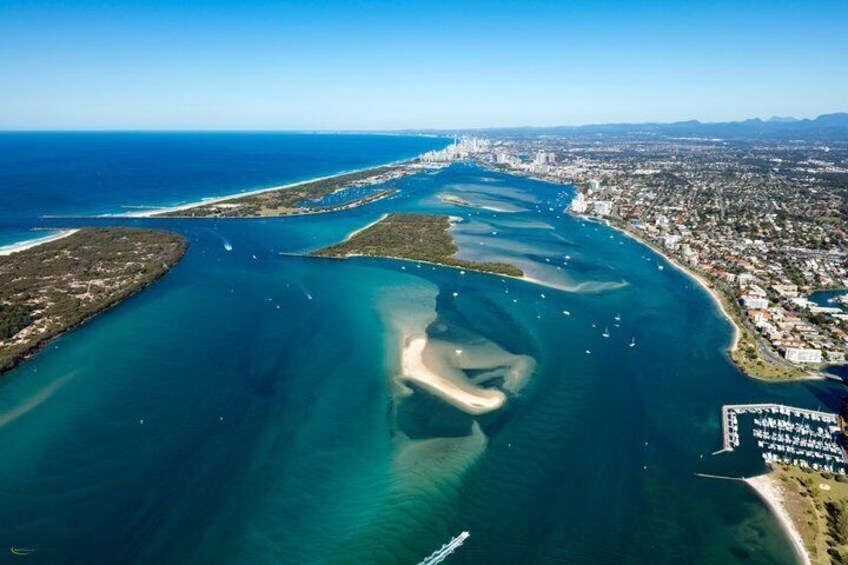 Vue aérienne d’une ville côtière avec un port de plaisance, des eaux d’un bleu limpide et une vaste baie. 3