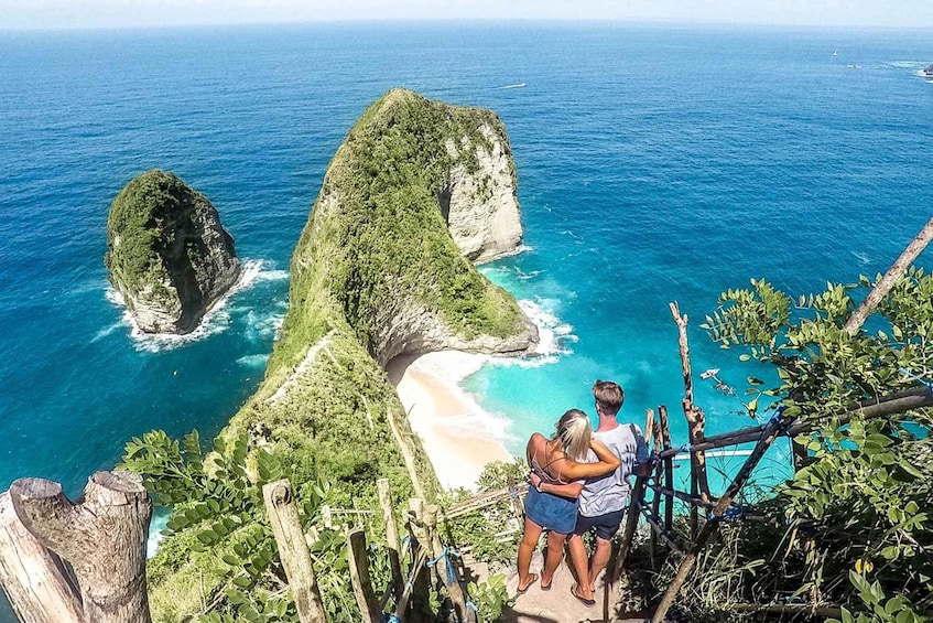 A couple overlooking a coastal landscape with prominent rock formations and a beach. 1
