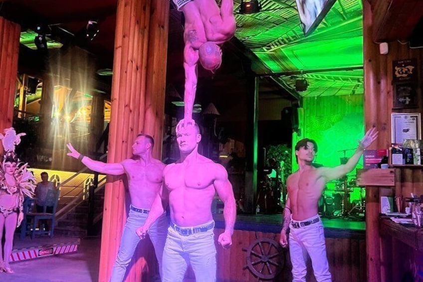 Un bar con travi in legno, un uomo che esegue un'acrobazia e una donna in costume. 1