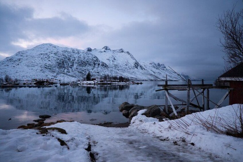 Una montagna innevata, un lago calmo e un molo di legno. 1