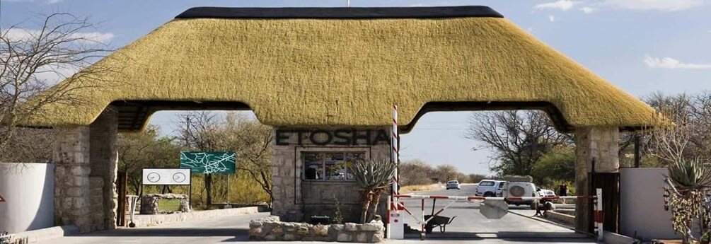A thatched-roof structure with a sign reading 'ETOSHA' and a gate with a barrier. 5