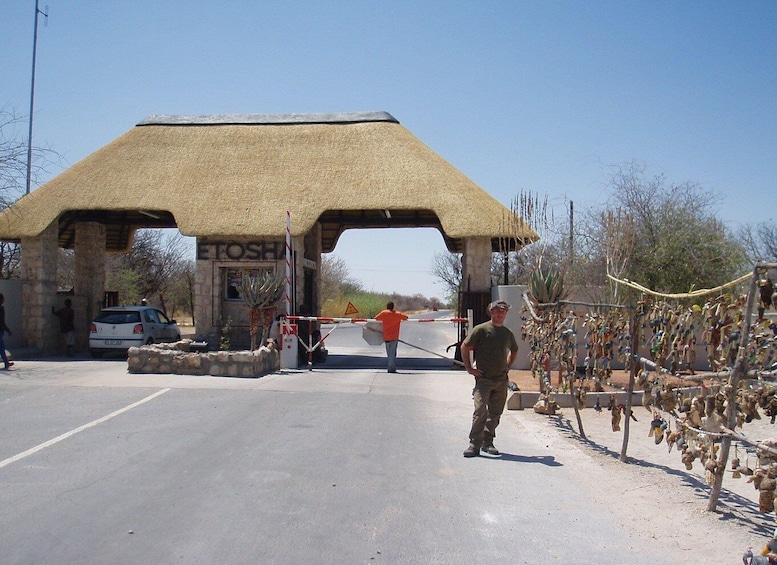 A thatched-roof structure with a sign reading 'ETOSHIN' and a man standing in front. 3