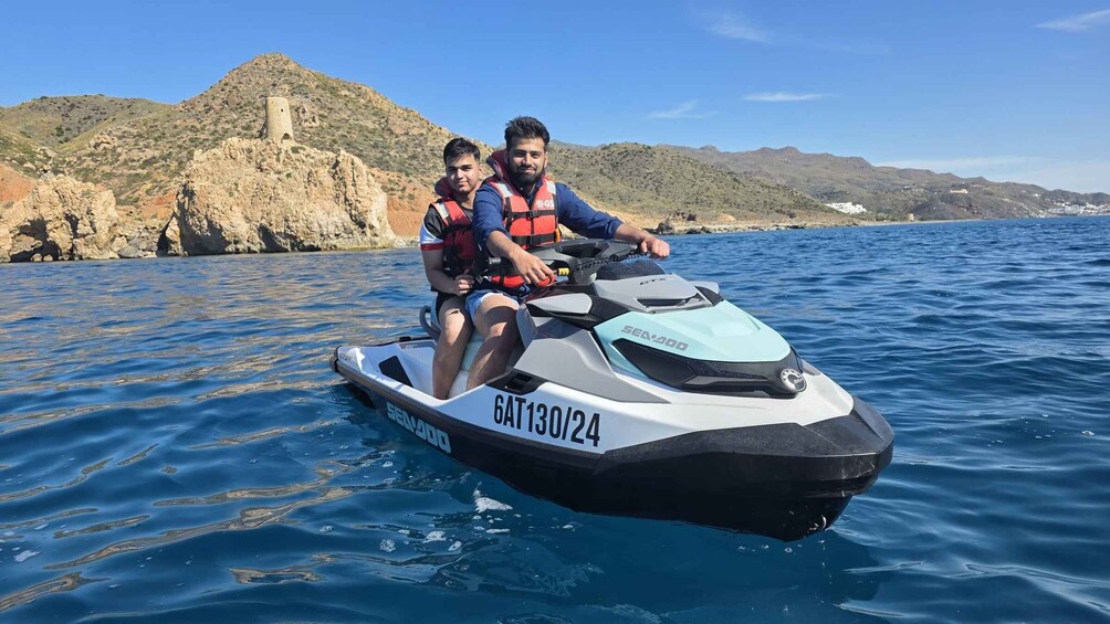 Two people on a jet ski with a mountainous landscape in the background. 2