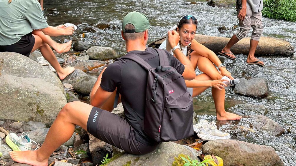 People sitting on rocks by a flowing river. 4