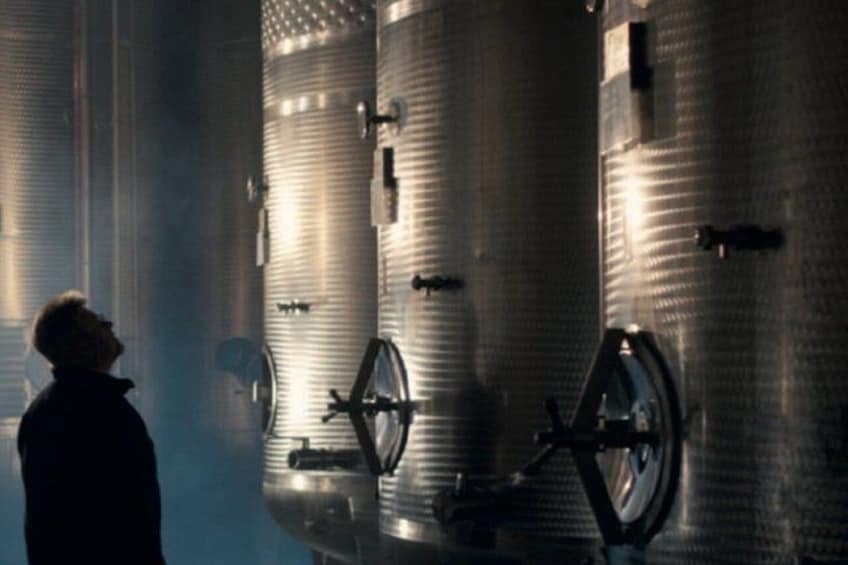 A person standing in front of large industrial tanks. 1