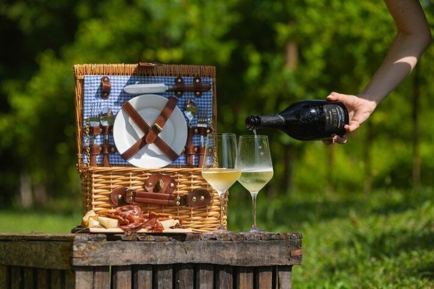 Ein Picknick mit einem Korbwägelchen, Weingläsern und einer angegossenen Flasche. 1