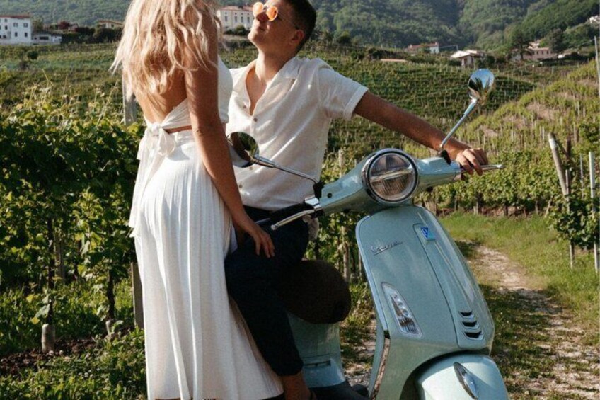 A couple on a vintage scooter in a vineyard. 1