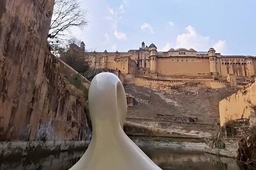 Eine große weiße Skulptur im Vordergrund, ein historisches Gebäude mit Kuppeln im Hintergrund und ein ausgetrocknetes Flussbett. 5