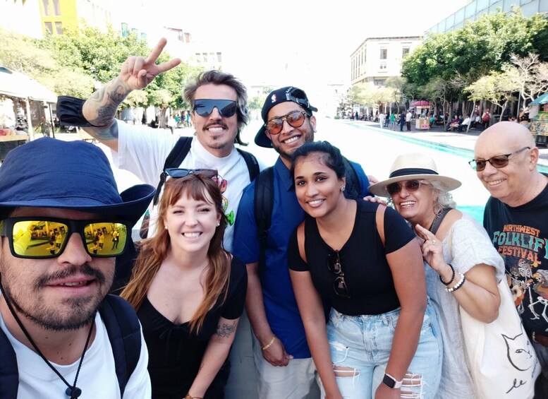 A group of people posing for a photo on a city street with buildings and trees in the background. 5
