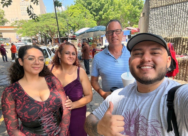 A group of people standing outdoors with a market in the background. 2