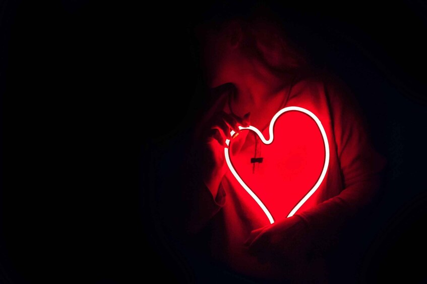 A person holding a glowing red heart-shaped object. 2