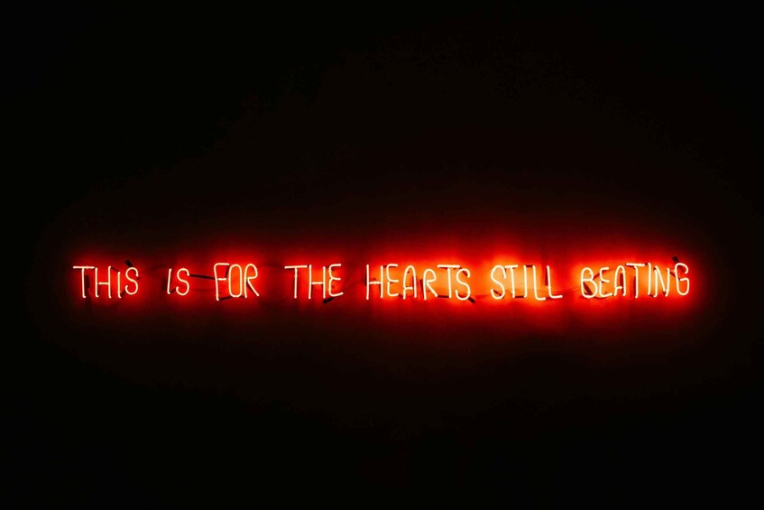 A neon sign with the text 'THIS IS FOR THE HEARTS STILL BEATING' in red. 4