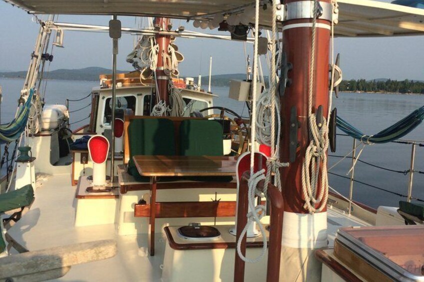 A boat deck with a table, chairs, and a hammock. 3