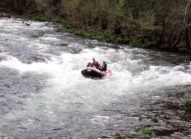 A white water rafting trip with two people in a raft navigating rapids. 2