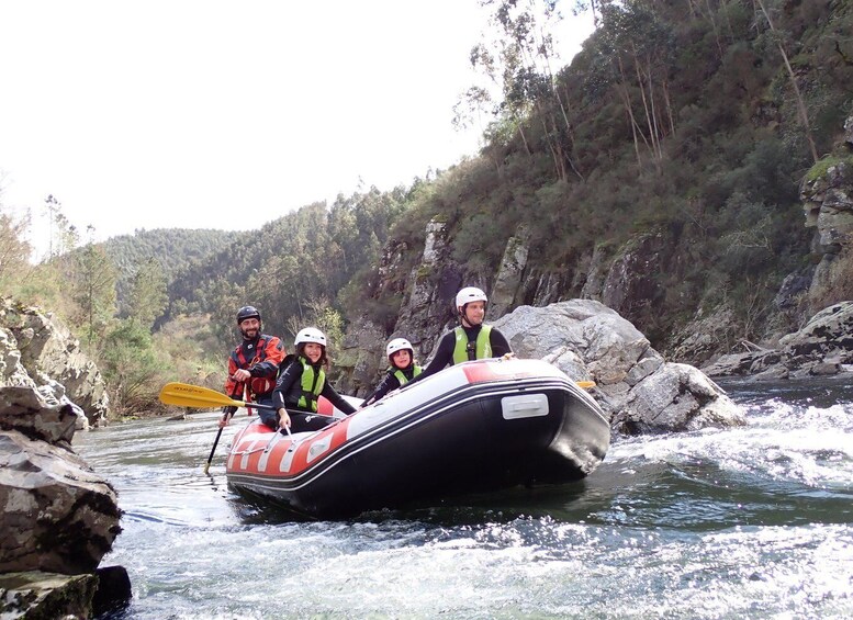 A group of people in a raft navigating a river surrounded by rocky terrain and dense forest. 3