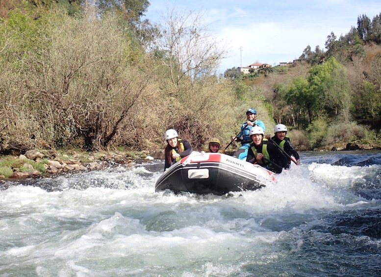A group of people in a white inflatable raft navigating a river surrounded by trees and hills. 1