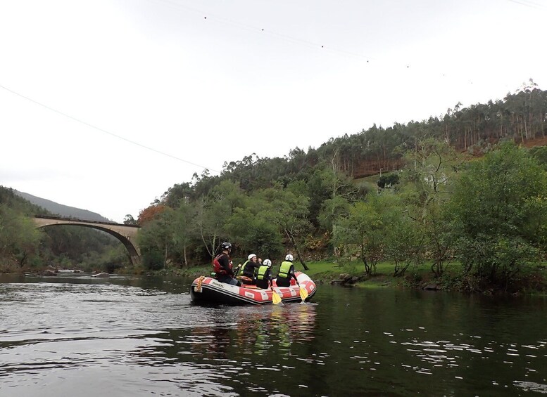 A river with a bridge in the background and a group of people in a raft. 4