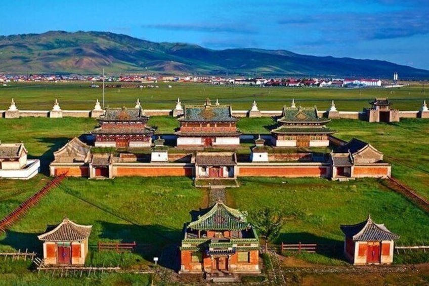 A traditional village with multiple buildings, a central pathway, and a distant mountain range. 1
