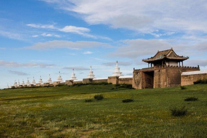 A series of white stupas, a traditional Chinese gate, and a white pagoda in a grassy field. 3