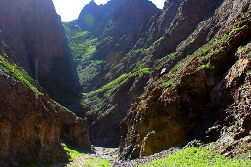 A canyon with steep rock walls and a narrow stream. 5