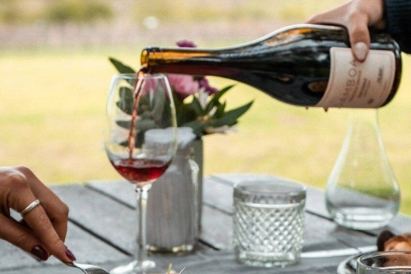 En person hælder vin i et glas. 3