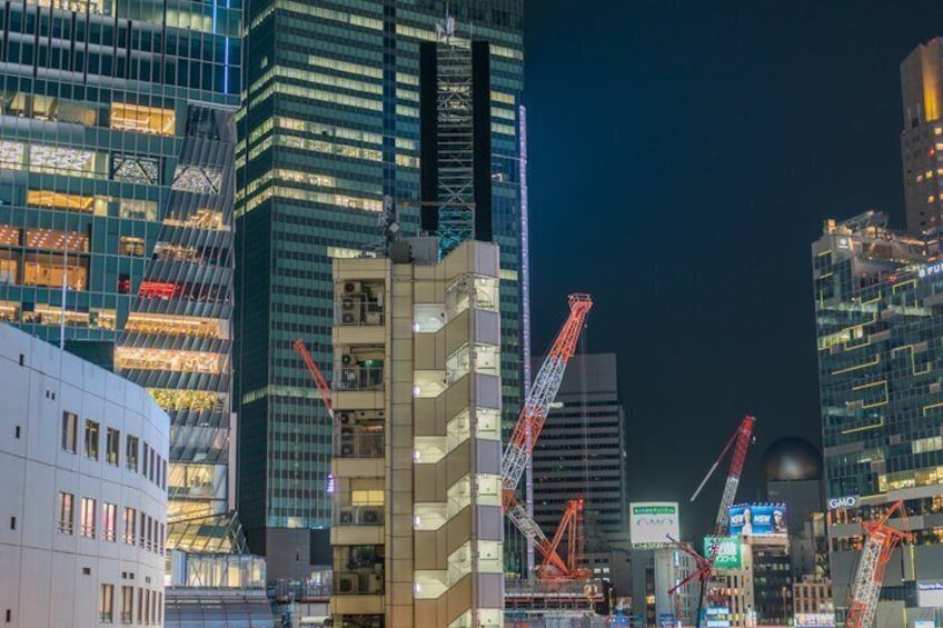 Une vue nocturne d’une ville, avec des gratte-ciel illuminés et des grues de chantier. 5
