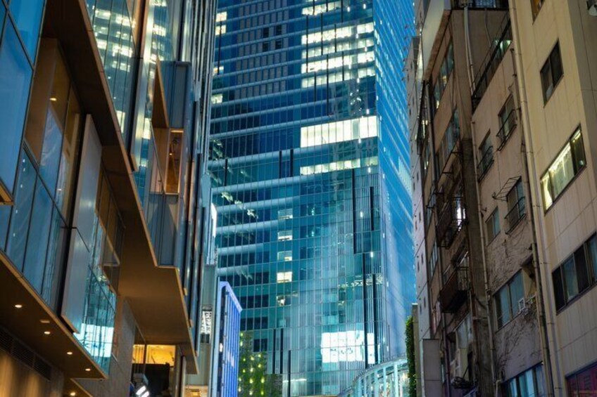 Une rue moderne en milieu urbain, bordée d’immeubles de grande hauteur aux façades vitrées réfléchissantes, sous un ciel dégagé. 2