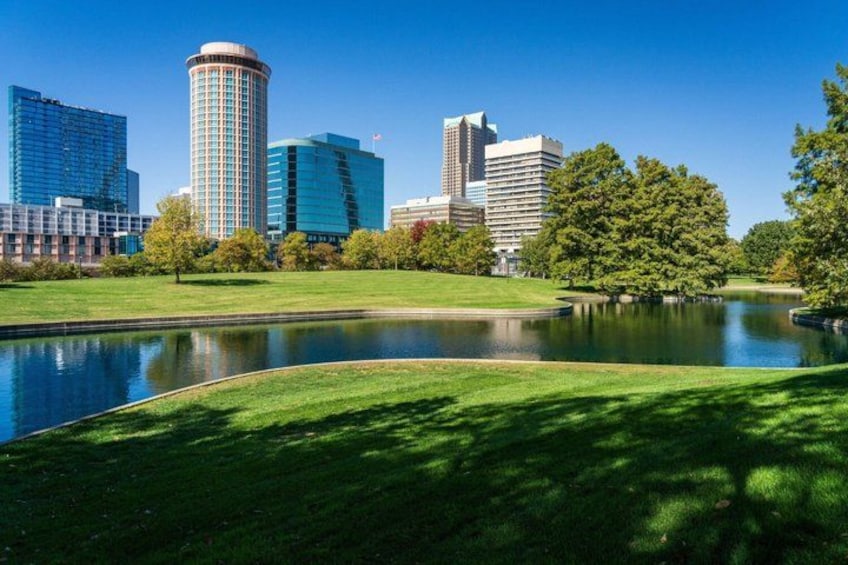 Een stadsgezicht met moderne gebouwen, een park met een vijver en bomen. 2
