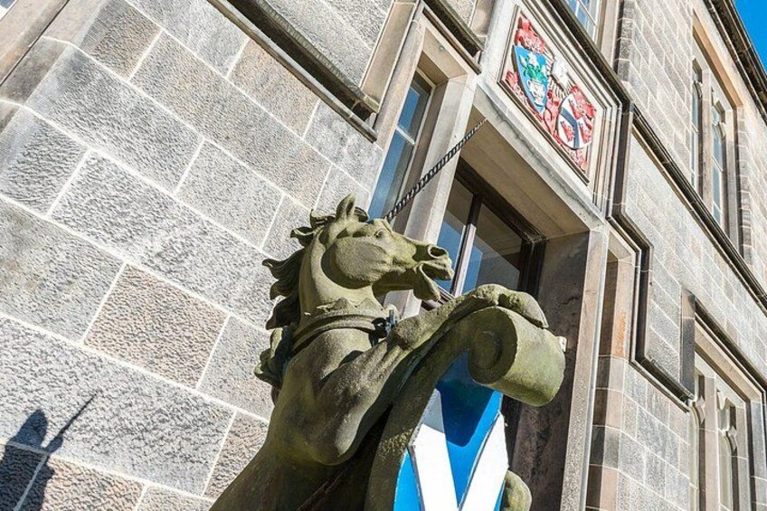 A stone horse statue in front of a building with a blue and white flag. 2