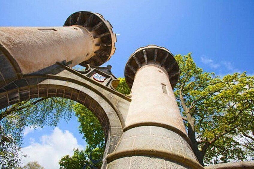 A stone tower with a large cannon, surrounded by trees and a clear sky. 2