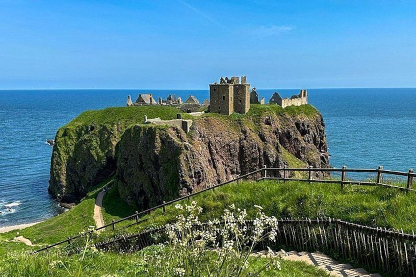 A coastal castle on a grassy cliff overlooking the sea. 4