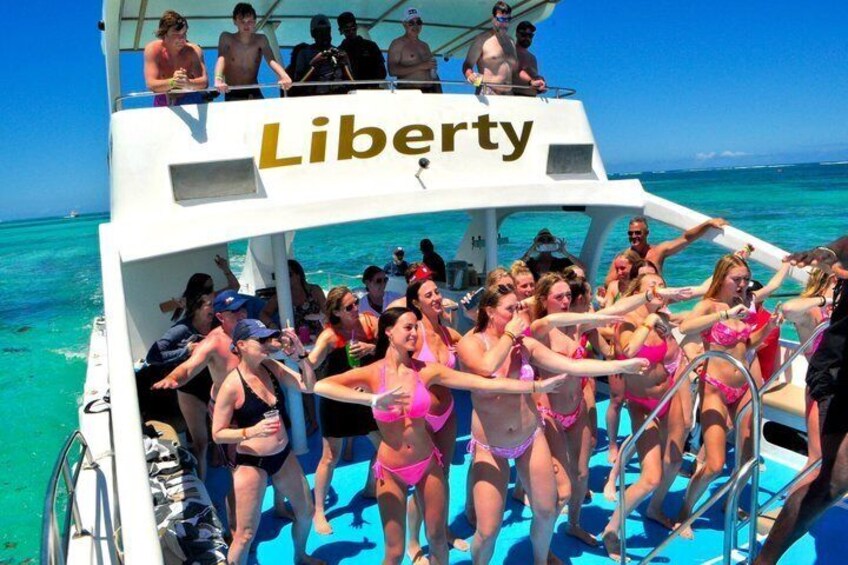 A group of people on a boat named Liberty, with clear turquoise water and a bright blue sky in the background. 1