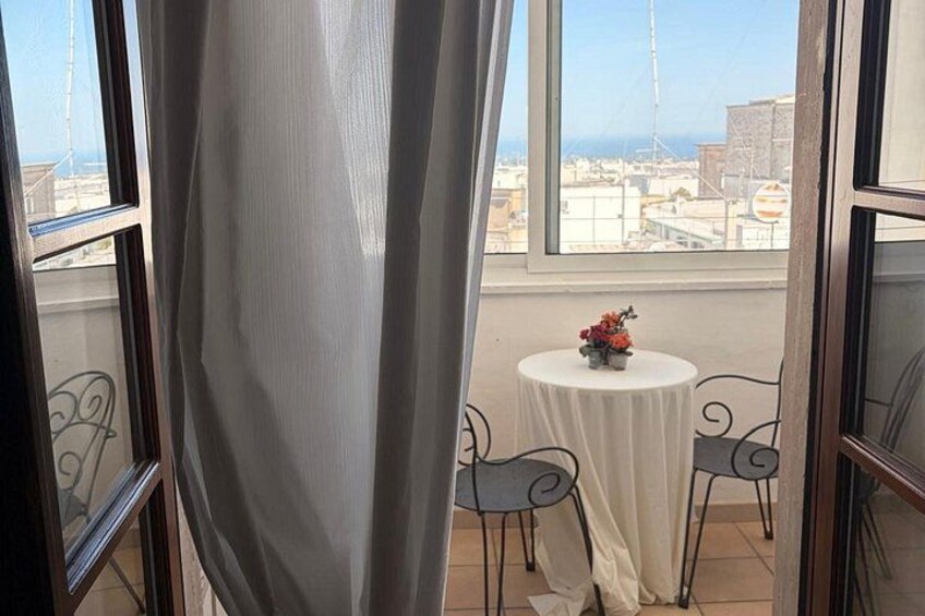 A balcony with a table and chairs, a curtain, and a view of the cityscape. 4