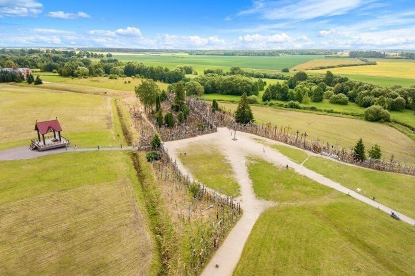 A rural landscape with a gazebo, a fenced area, and a dirt path. 3