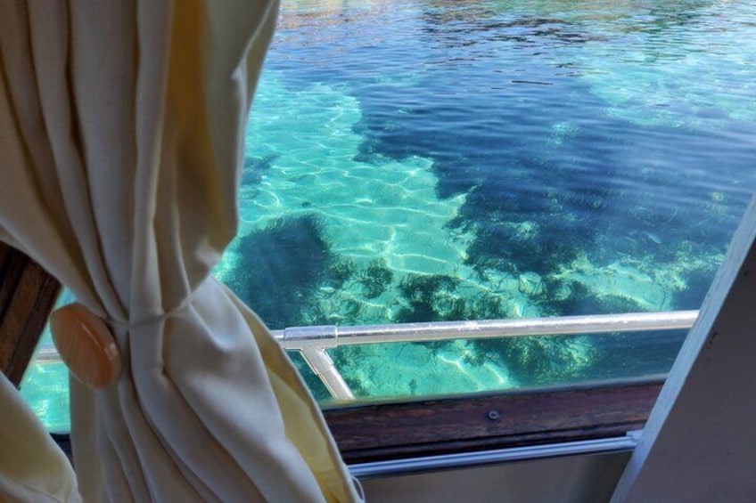 Vista de agua azul cristalina con vegetación submarina visible desde una ventana. 4