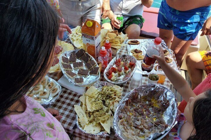 Un grupo de personas alrededor de una mesa con diversos alimentos y bebidas. 5