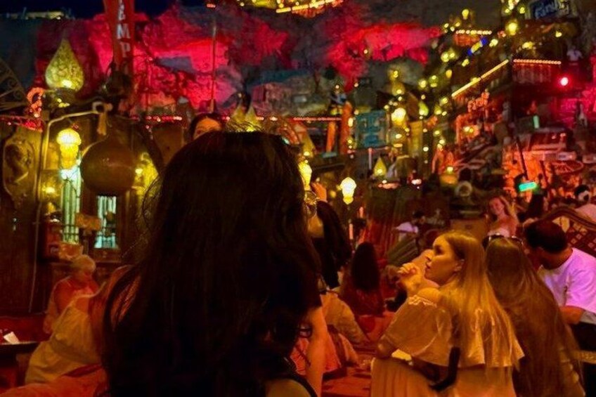 Un mercado interior concurrido, con varios puestos y letreros iluminados. 5
