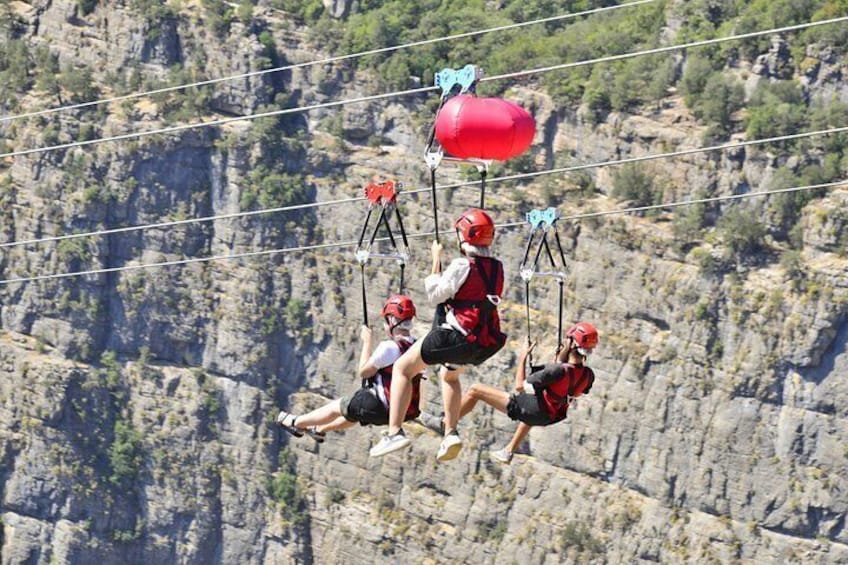 A group of people engaged in a zip-lining activity over a rocky cliff. 4