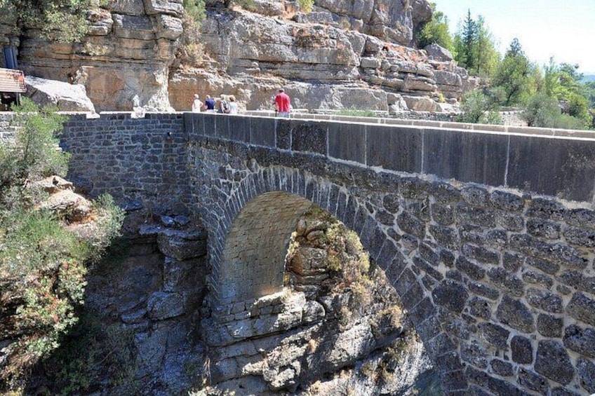 A stone bridge with a tunnel entrance, surrounded by rocky terrain and vegetation. 5