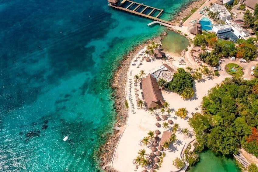 Un resort costero con playa, aguas turquesas cristalinas y un muelle. 3
