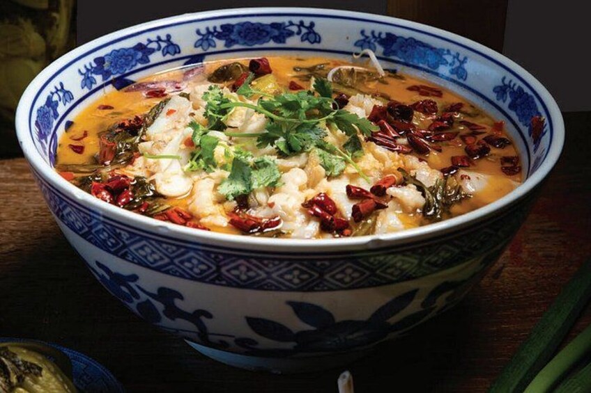 Una ciotola di zuppa con un decoro blu e bianco, guarnita con coriandolo e scaglie di peperoncino. 1