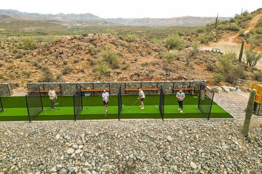 En golf driving range med flere tee-spots og spillere. 4