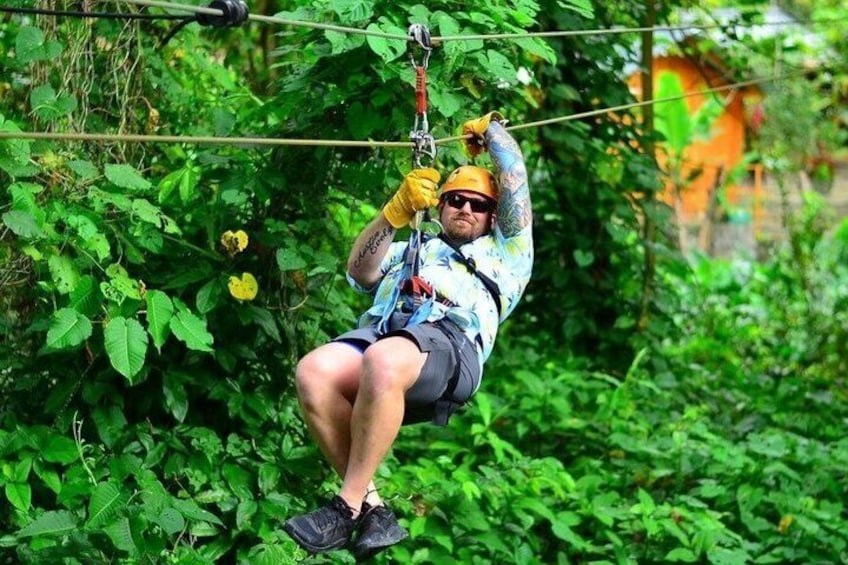 A person zip-lining through a lush green forest. 4