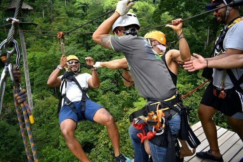 People bungee jumping with safety harnesses and helmets, surrounded by lush greenery. 5