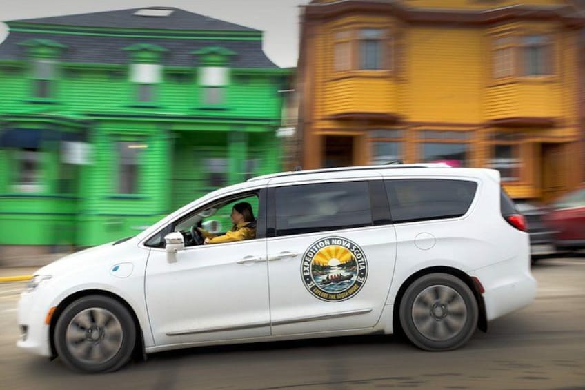 A white car with a logo on the side driving on a street. 3