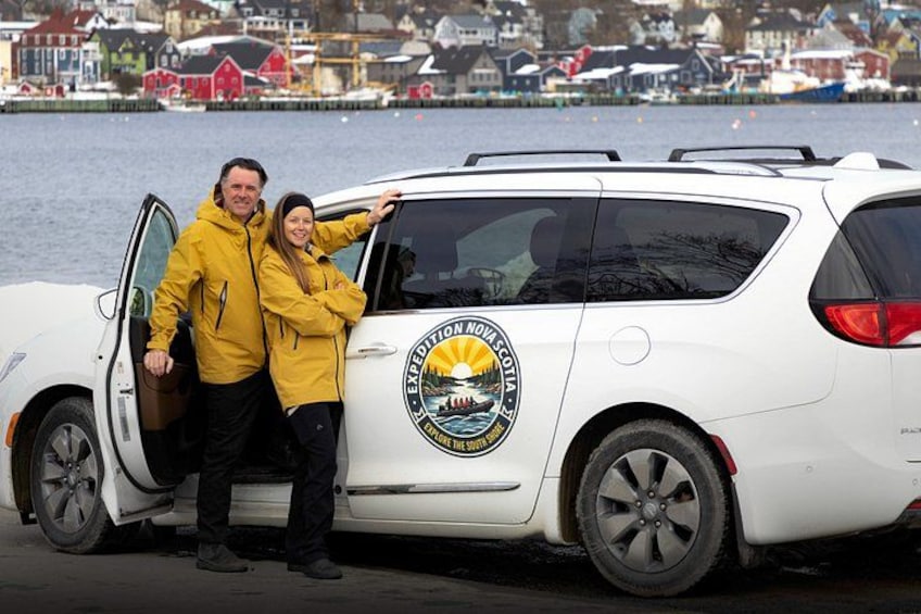 A white vehicle with a logo and two people standing beside it. 2